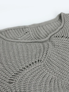 Detail of light gray knit sweater showing ribbed crew neck and delicate hollow pattern