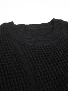 Detailed macro view of black knit sweater featuring waffle texture and cable stitch patterns