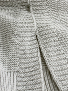 Close-up detail of light gray knitted cardigan showing fine texture and stitching