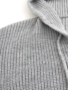 Detail of light grey chunky knit texture and ribbed neckline on a hooded cardigan