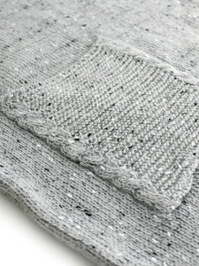 Close-up of women's grey knitted sweater dress featuring a textured pocket with woven trim