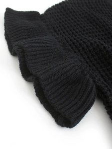 Detailed close-up of black knitted sweater showing ribbed cuffs and honeycomb stitch