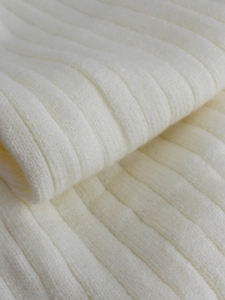 Detailed close-up of cream-colored thick ribbed knit fabric with soft texture