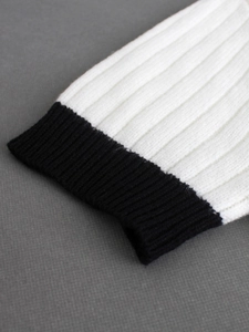 Détail de l'ourlet tricoté contrasté sur un pull à manches courtes blanc cassé et noir