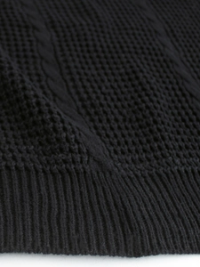 Detail of black cable knit sweater featuring thick texture and ribbed hem finish