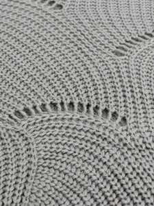 Macro shot of gray knitted pullover fabric showing tight knit pattern and hollow design