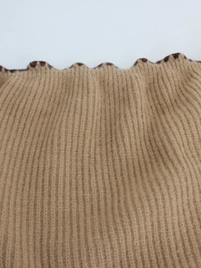 Detail of khaki ribbed knit fabric featuring a dark brown wavy lettuce trim finish