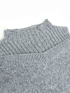 Close-up of light gray knitted sweater with high collar and ribbed texture detailing