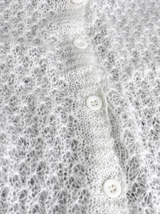 Makrodetail der weißen Mohair-Strickjacke mit Lochmuster und passenden Knöpfen