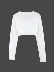 Close-up of white ribbed knit cropped shrug showing fine texture on grey background