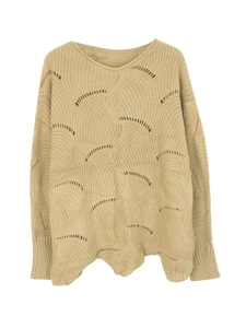 Detail of beige knit sweater showing hollow crochet patterns and wavy scalloped hem