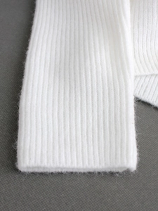 Close-up of white ribbed knit crewneck sweater featuring soft wool texture and long sleeves