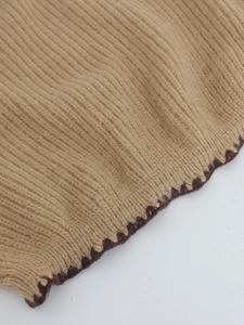 Close-up of khaki ribbed knit fabric with dark brown wavy stitched edge detail