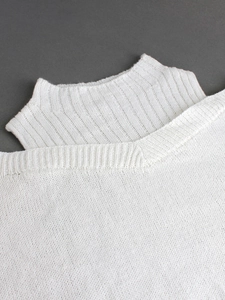 Detail of white turtleneck knit sweater with V-neck layering and ribbed texture