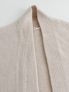 Close-up of cream knit long cardigan showing soft woven texture and neckline details