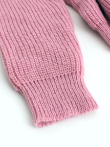 Gros plan du poignet côtelé d'un pull en tricot rose montrant la texture épaisse