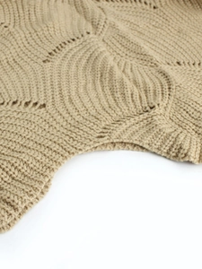 Macro view of beige knit sweater showing wavy texture and delicate hollow-out details