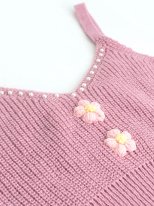 Détail du caraco en tricot rose avec bordure en perles et fleurs 3D appliquées