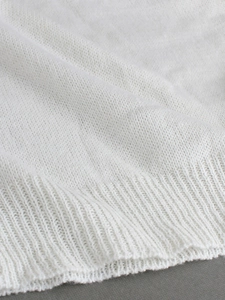 Detailed macro view of white knit sweater fabric texture with ribbed hem stitching
