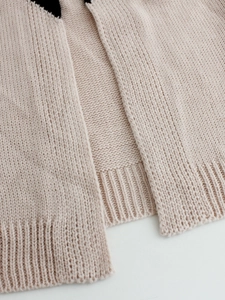 Close-up of beige knit cardigan showing premium ribbed hem and soft fabric texture detail