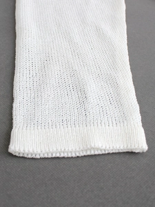 Close-up of white knit sweater cuff showing detailed mesh texture and breathable fabric