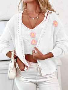 Détail de maille du cardigan blanc avec fleurs roses 3D et boutons en résine