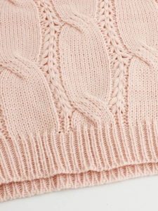Close-up of soft pink cable knit pattern and ribbed hem on long sleeve sweater