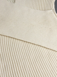 Close-up of cream white ribbed knit sweater featuring a refined V-neck overlap detail