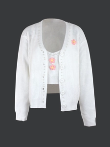 Détail d'un cardigan blanc avec bordure en perles et fleurs au crochet roses
