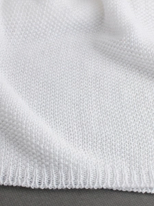 Close-up of white knit fabric texture showing fine weave and ribbed hem detail