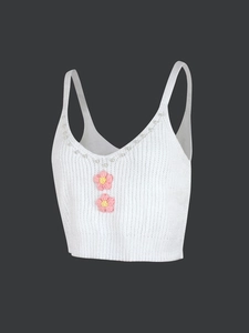 Détail d'un caraco en tricot blanc avec encolure en perles et fleurs au crochet roses