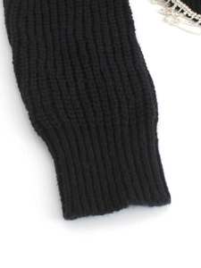 Close-up of black knit sweater cuff with ribbed texture and rhinestone chain detail