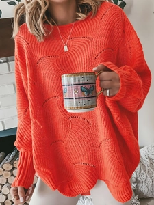 Close-up of orange knit sweater showing intricate wavy hollow out texture and ribbed cuffs
