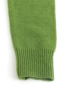 Primo piano del cardigan in maglia verde erba con polsini a costine e tessuto morbido