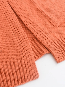 Gros plan détaillé d'un pull en maille orange avec des textures côtelées