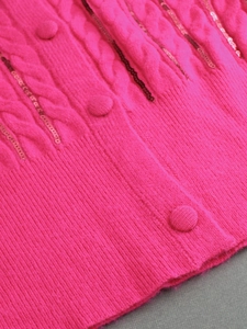 Macro detail of rose pink cable knit sweater featuring sequins and fabric covered buttons