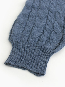 Detail of dark blue cable knit texture and ribbed cuff on a long sleeve sweater