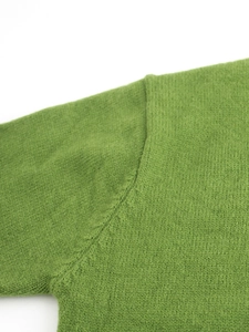 Dettaglio della cucitura sulla spalla di questo cardigan in maglia verde primaverile