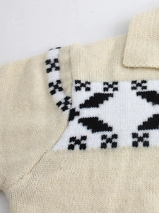 Dettaglio del cardigan in maglia crema con motivi geometrici jacquard bianchi e neri