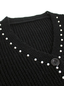Détail d'un cardigan noir en maille côtelée avec perles blanches et bouton