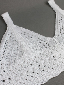White crochet knit crop top with intricate hollow-out floral patterns and V-neckline