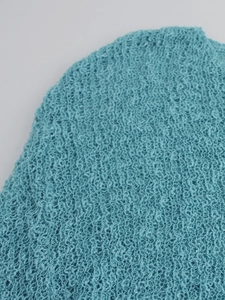 Gros plan sur le tissu en maille bleu clair avec texture ajourée et franges