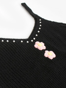 Détail du cardigan en maille col V avec perles et fleurs 3D sur tissu noir élégant