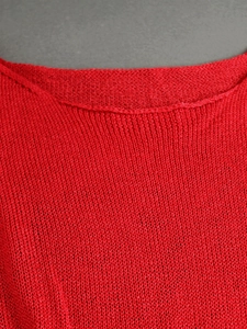 Detailed view of red knitted sweater neckline showing premium knit fabric texture
