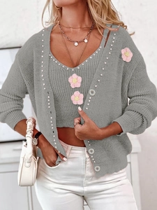 Détail d'un ensemble en maille gris avec gilet, caraco, fleurs roses et perles blanches