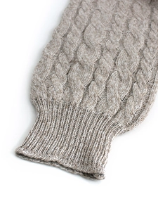 Detail of oatmeal cable knit sweater featuring textured sleeve cuffs and ribbed trim