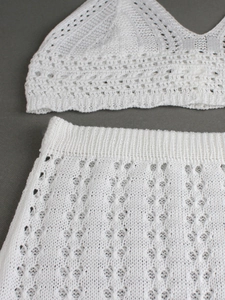 Detailed close-up of white crochet knit texture and hollow-out floral pattern on a two-piece set