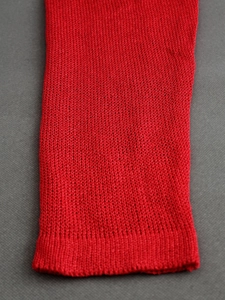 Detail of red thin knit sweater sleeve showing fine texture and ribbed elastic cuffs