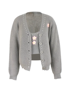 Détail d'un cardigan en tricot gris avec bordure en perles et broderies de fleurs
