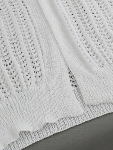 Close-up of white crochet knit fabric showing intricate geometric hollow-out patterns